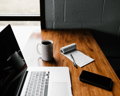 Detail of a workspace setup with notebook and a warm mug