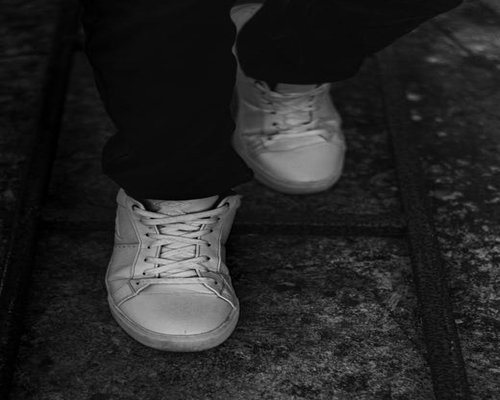 Legs of a person wearing comfortable sneakers walking on city pavement