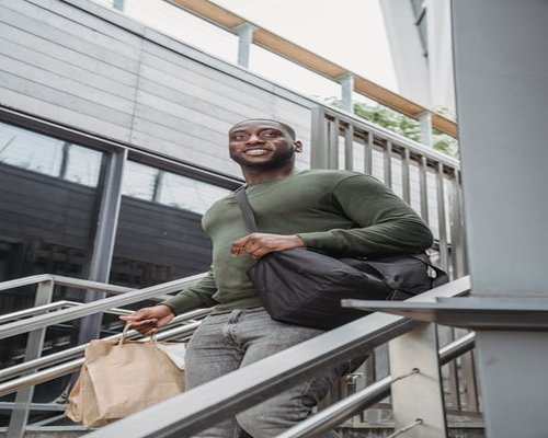 A person slowly walking up the stairs carrying a light shopping bag
